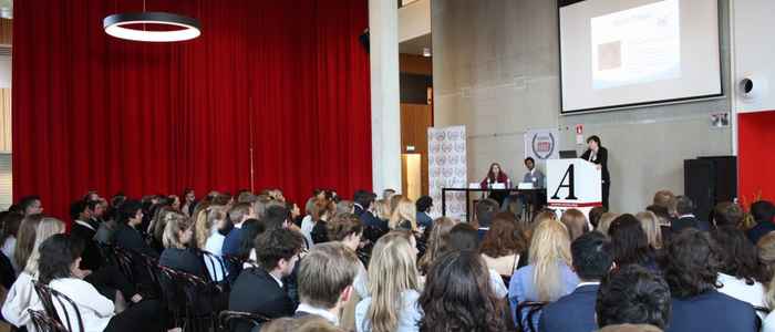 AUC MUN Conference wide shot showing students presenting on stage and an audience